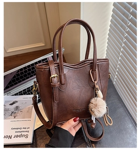 Dettaglio di borsa marrone in pelle PU con doppi manici e ciondolo a pompon morbido
