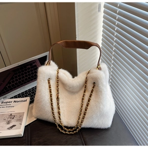Detail of white faux fur handbag with brown leather handles and golden chain straps