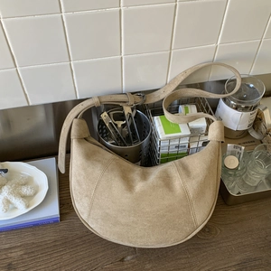 Dettaglio di una borsa a tracolla a mezzaluna in camoscio beige con tracolla regolabile