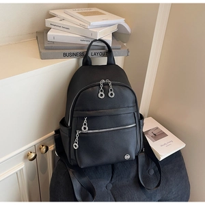 Detail of black lychee grain leather backpack with silver ring zippers and chain accents