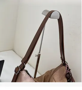 Detail of reinforced wide leather handle with stitching on khaki shoulder bag