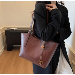 Detail of dark brown faux leather tote with adjustable strap and wood bead tassel