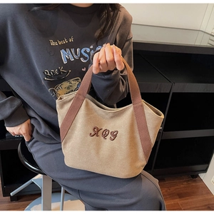 Detailed close-up of khaki canvas tote bag featuring premium brown XQG letter embroidery