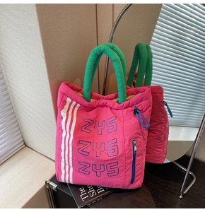 Detail of pink quilted tote bag with green handles and a small blue zipper pocket