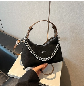 Détail du sac à main en daim noir avec chaîne argentée et poignée en cuir brun