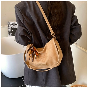 Detail view of khaki suede hobo bag with colorful bead tassels and logo leather patch