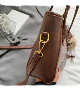 Dettaglio della borsa vintage marrone in pelle con ferramenta dorata e ciondolo peluche