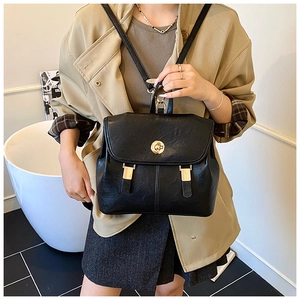 Detail of a vintage black PU leather backpack with a gold swivel lock on a model