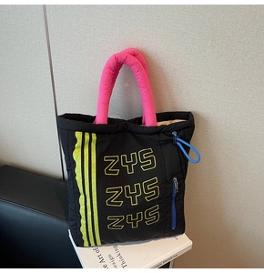 Detail of black puffer tote bag featuring pink handles and blue drawstring adjustments