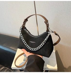 Détail du sac hobo en daim noir avec bandoulière en cuir marron et chaîne argentée