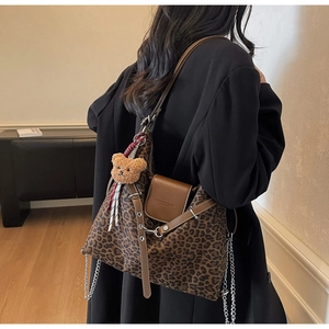 Side view of leopard print tote bag with brown leather flap and bear charm on model