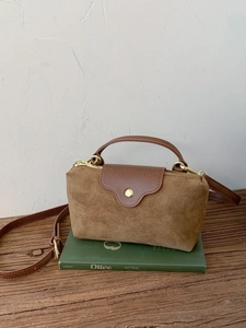 Vintage brown suede and leather crossbody bag with gold hardware on a wooden surface