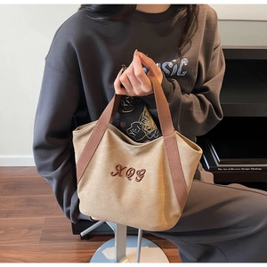 Close-up of the vintage XOG embroidery on the khaki canvas tote bag with woven handles