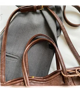 Dettaglio dei manici e della tracolla regolabile di una borsa a secchiello marrone retrò