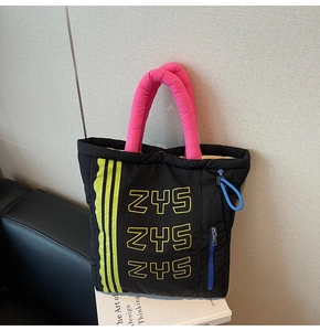 Close-up of black quilted tote bag with pink padded handles and ZYS lettering detail