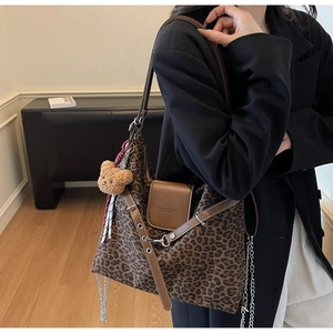 Leopard print tote bag detail showing brown leather flap, chain, and plush bear charm
