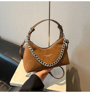 Détail d'un sac demi-lune en daim marron avec chaîne argentée et bandoulière en cuir