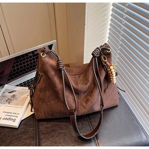 Detail der Kontrastnähte und Holzperlen am dunkelbraunen Wildleder-Hobo-Bag