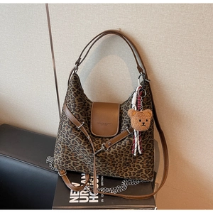 Close-up of leopard print canvas tote bag featuring brown leather trim and bear charm