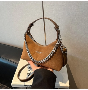 Gros plan du sac hobo en daim marron avec chaîne argentée et lettrage blanc élégant