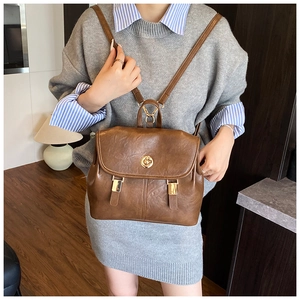 Detail of vintage brown leather backpack showing gold twist lock and retro strap design