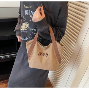 Close-up of beige canvas tote bag with brown XQG embroidery and sturdy handles