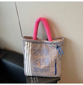 Macro shot of quilted grey tote with pink padded handles and side stripe details