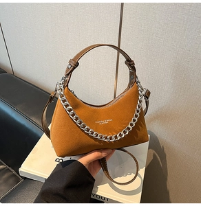 Détail du sac en daim marron avec chaîne argentée épaisse et anse en cuir