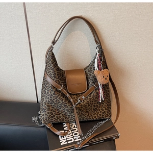 Detailed macro view of leopard print tote bag with brown leather trim and bear charm