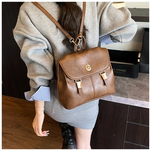 Rear view of model wearing a vintage brown leather backpack with golden twist lock detail