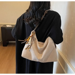 Makroansicht der beige Wildleder Hobo-Tasche mit weicher Textur und ethnischer Perlenquaste