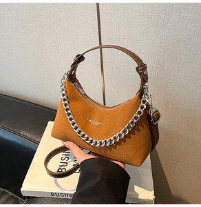 Détail du sac demi-lune en daim camel avec chaîne argentée et finitions en cuir lisse