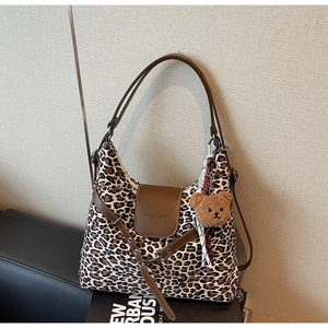 Detailed close-up of leopard print tote bag with brown leather flap and bear charm accessory