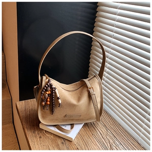 Close-up of beige suede crossbody bag with vintage wooden beads on a sunlit wooden step