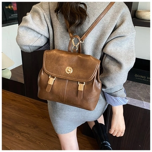 Rear view of model wearing a vintage brown faux leather backpack with gold buckle detail