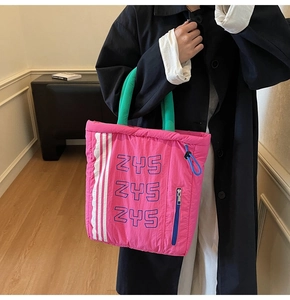 Close-up of pink canvas tote bag showing green round handles and zipper detail