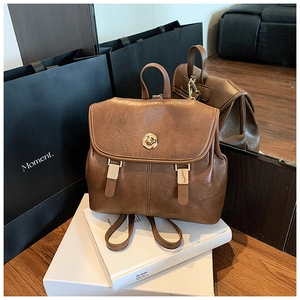 Close-up of vintage brown leather backpack with golden metal turn-lock and strap details