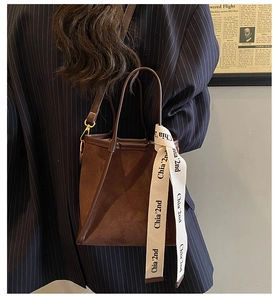 Détail d'un sac seau en daim marron avec bandoulière réglable et ruban en toile élégant