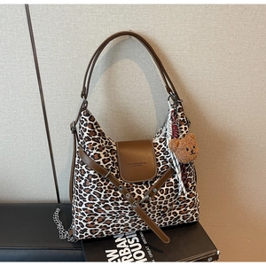 Detailed close-up of leopard print hobo bag with leather trim and fashion bear charm