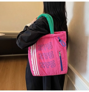 Detail of hot pink nylon tote bag showing color-block handles and ZYS lettering print