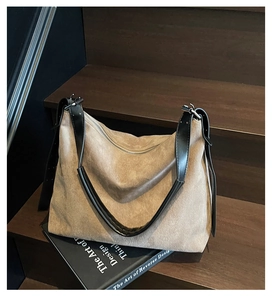 Gros plan d'un sac hobo en daim kaki avec des lanières en cuir noir sur bois