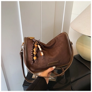 Close-up of vintage dark brown suede handbag with decorative wooden beads and brand emblem
