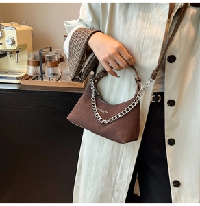 Sac croissant marron givré avec chaîne argentée dans un décor de café chic