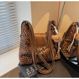 Detail of leopard print tote bag with brown leather trim and fluffy bear pendant charm