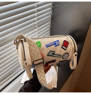 Dettaglio borsa a cilindro retrò con distintivi ricamati e tracolla jacquard