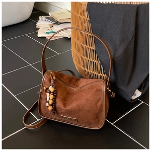 Detail of vintage brown suede crossbody bag with decorative wooden beads and metal hardware