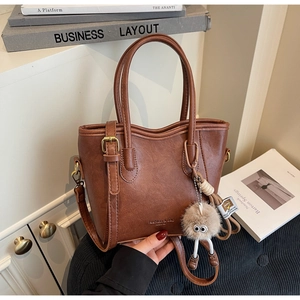 Dettaglio borsa a secchiello vintage marrone in pelle PU con ciondolo di peluche