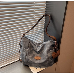 Detailed view of blue washed fabric tote bag with brown straps and brand logo patch