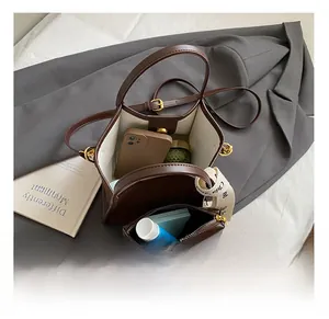 Vue intérieure du sac seau marron montrant sa grande capacité et sa petite pochette assortie