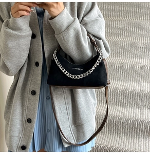 Détail d'un sac hobo noir avec garniture en cuir marron et chaîne argentée décorative
